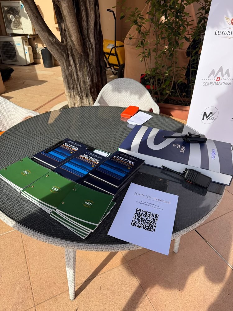 A courtside table with copies of the book, green folders and a Golden Era community QR code card